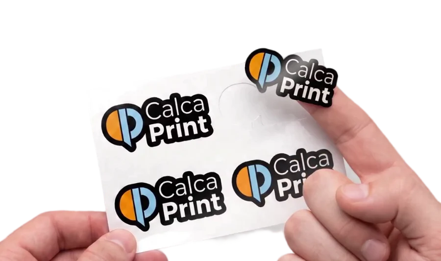 Mano que despega un sticker con el logo de Calcaprint de su pliego y lo muestra pegado en la yema del dedo; en el pliego queda el papel de respaldo con el contorno vacío
